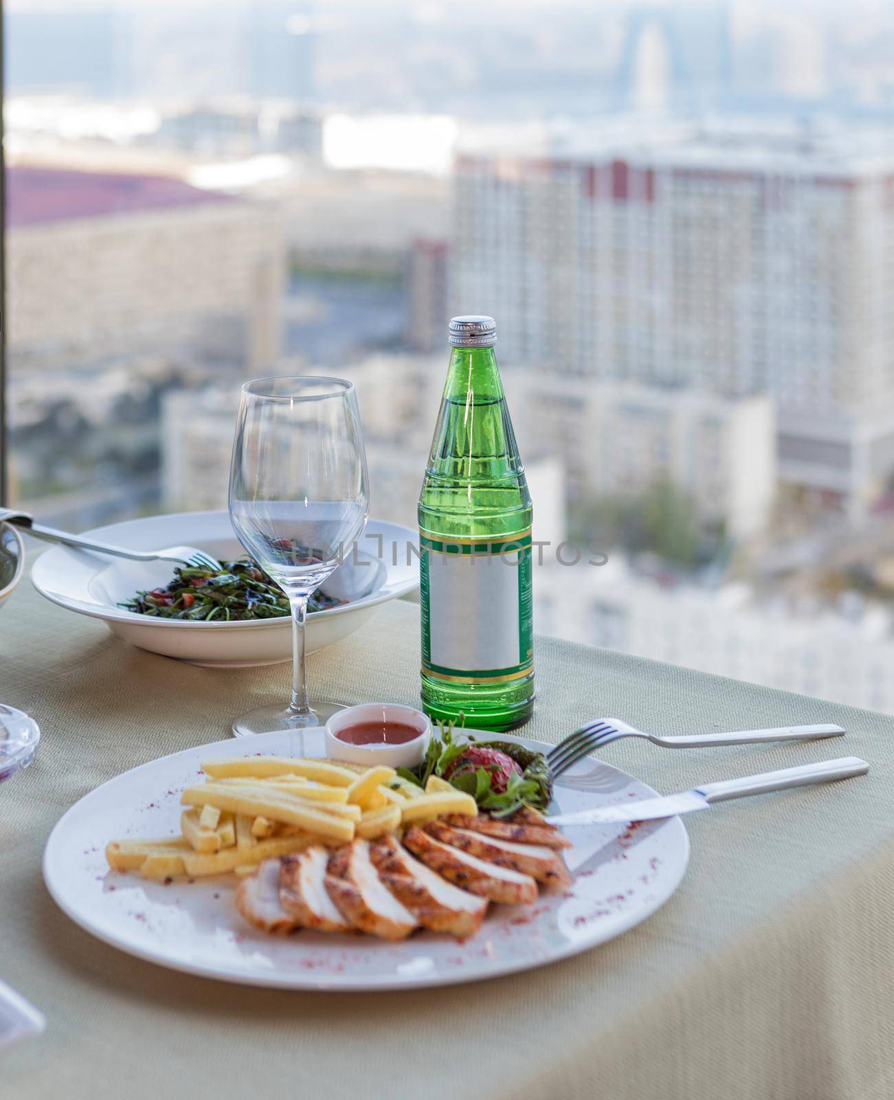 Fried chicken with french fries, water bottle and city view