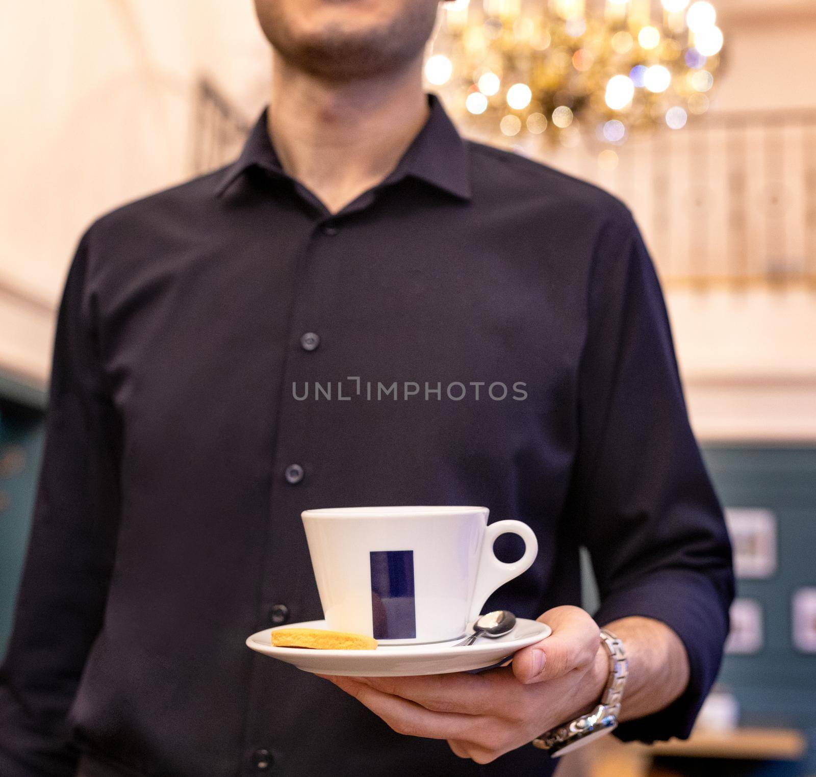 Waiter holding cup of coffee, tea at the restaurant by ferhad