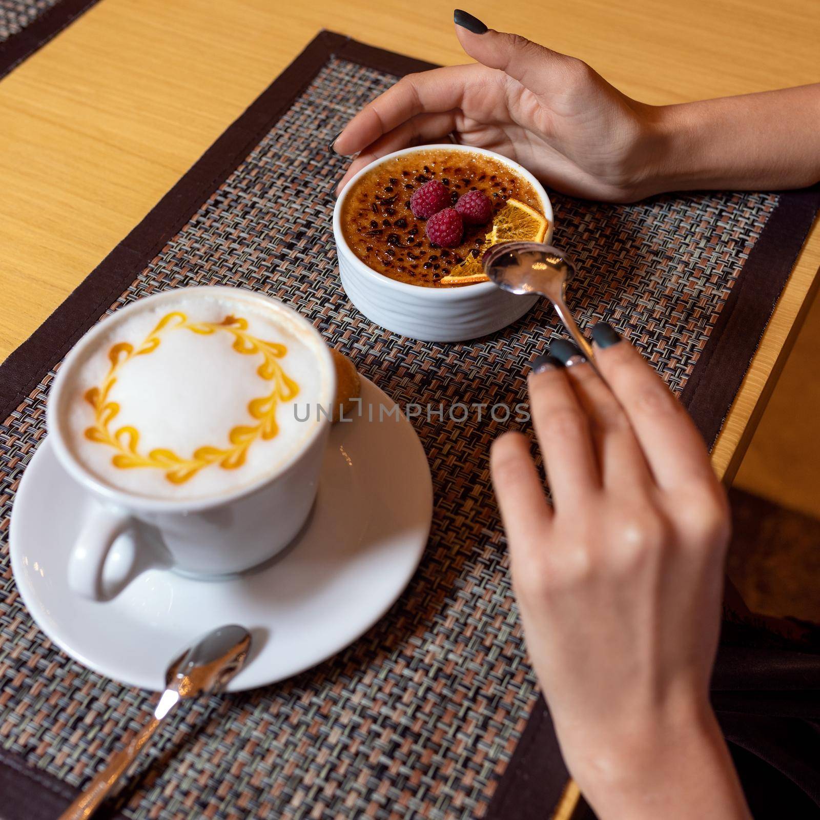 Woman eating raspberry dessert with latte coffee