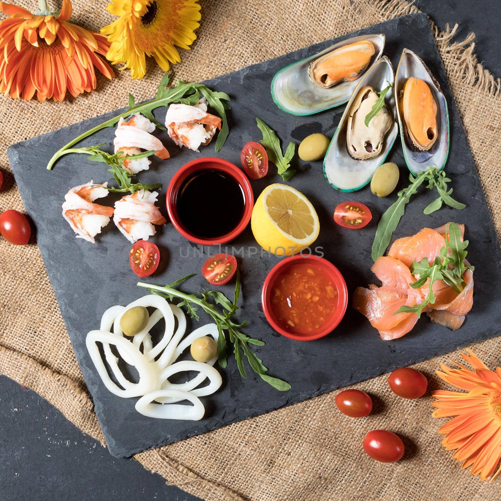 Fresh fish and seafood arrangement on black stone background