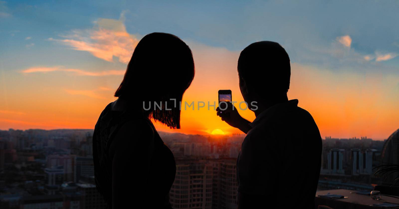 Couple taking photo of beautiful sunset city view by ferhad