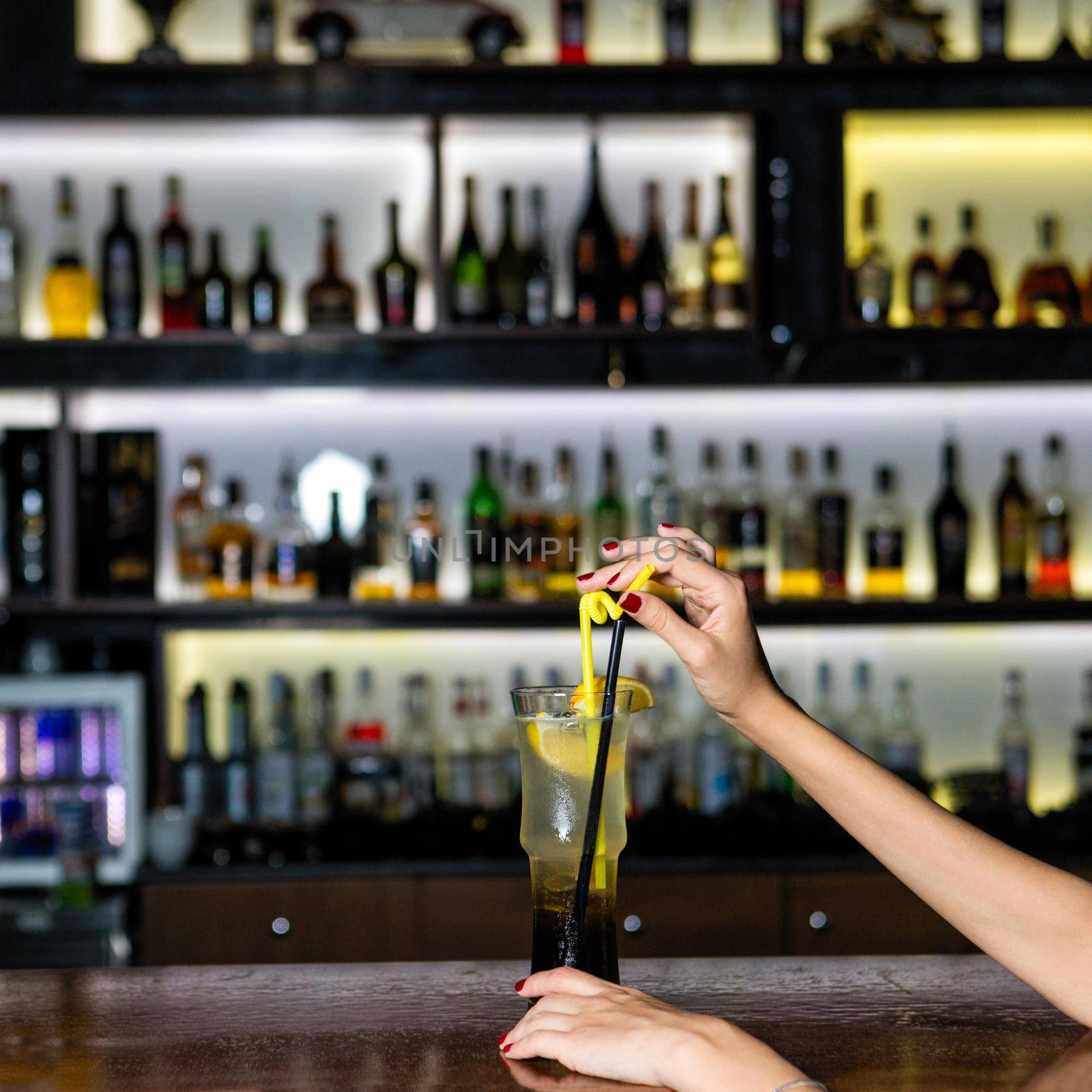 Woman holding lemon fruit cocktail at the bar