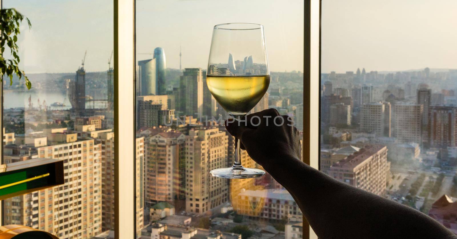Woman holding white wine glass with city view by ferhad