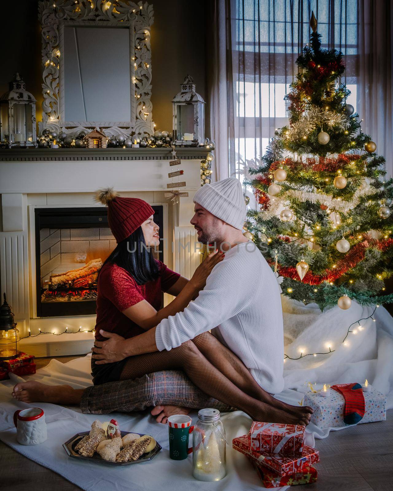 Family sitting on a floor. Couple near christmas tree, Christmas couple with present under christmas tree