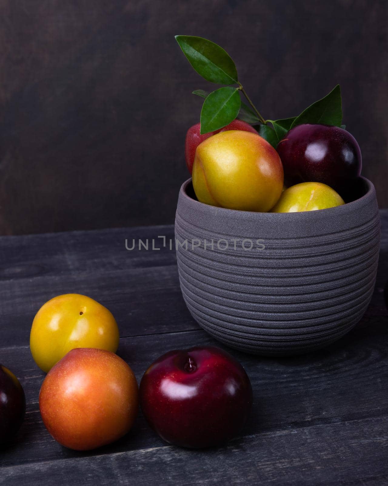 Colorful plums fruit in pot and plate on the black background isolated by ferhad