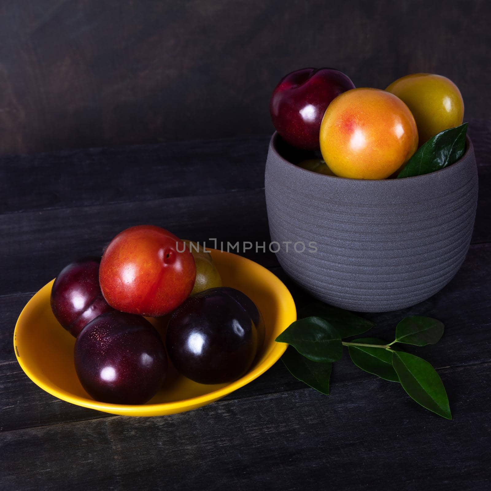 Colorful plums fruit in pot and plate on the black background isolated by ferhad