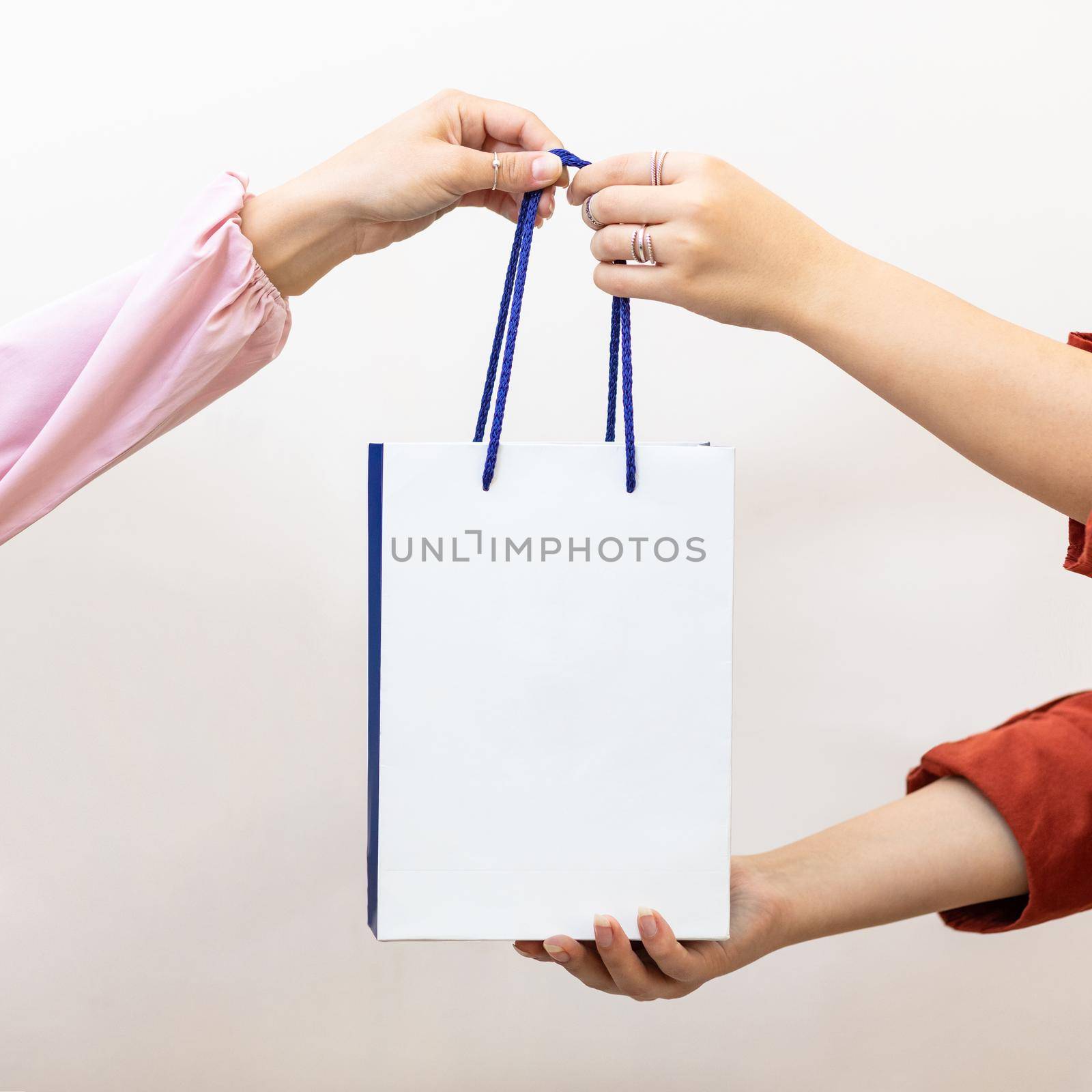 Woman giving a shopping bag to the another person by ferhad
