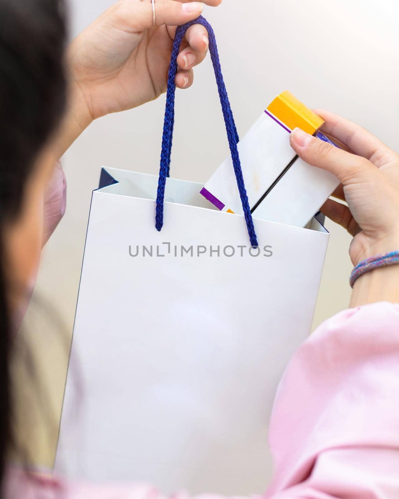 Woman putting box to the white shopping bag close up