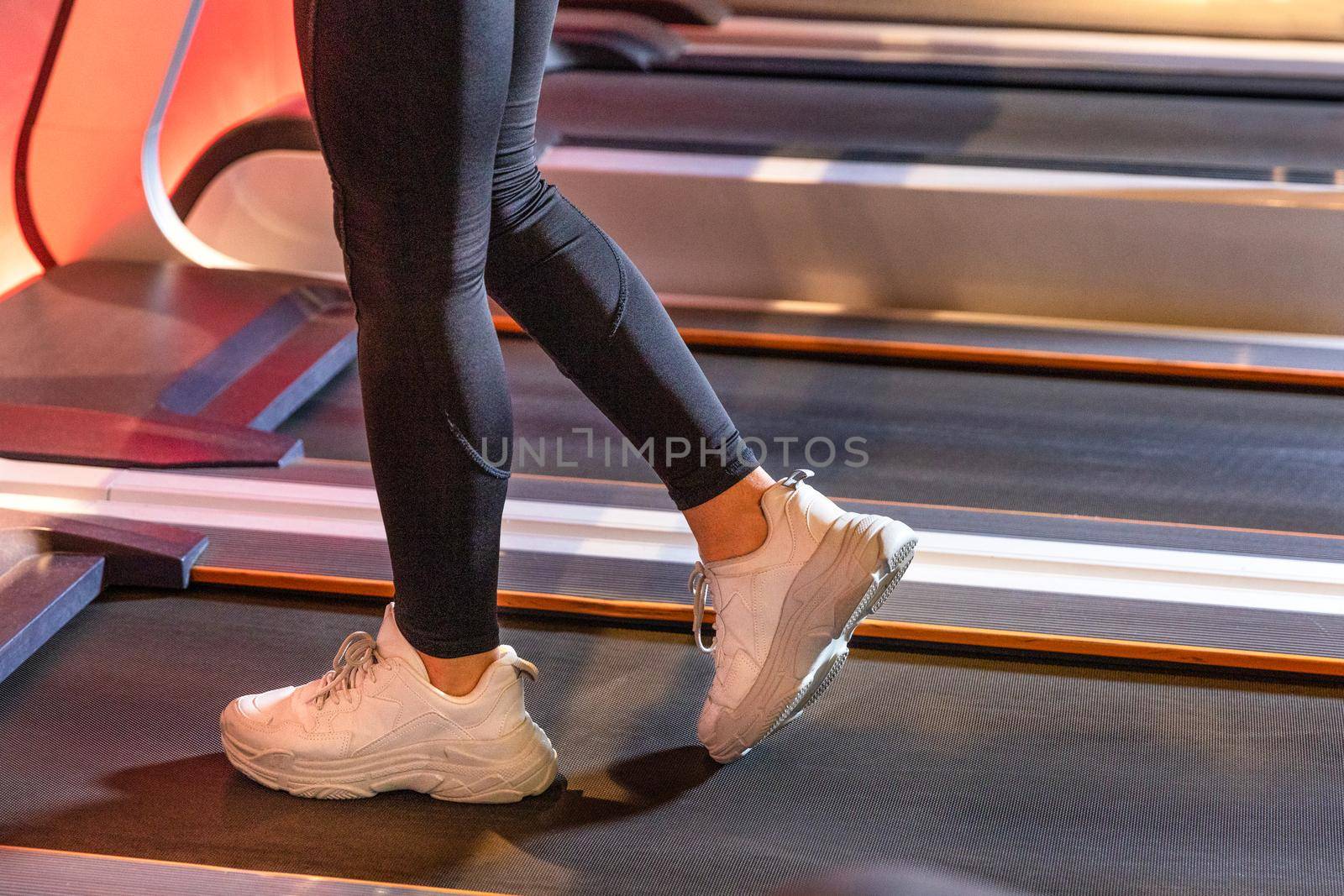 Fitness girl running on treadmill with white shoes