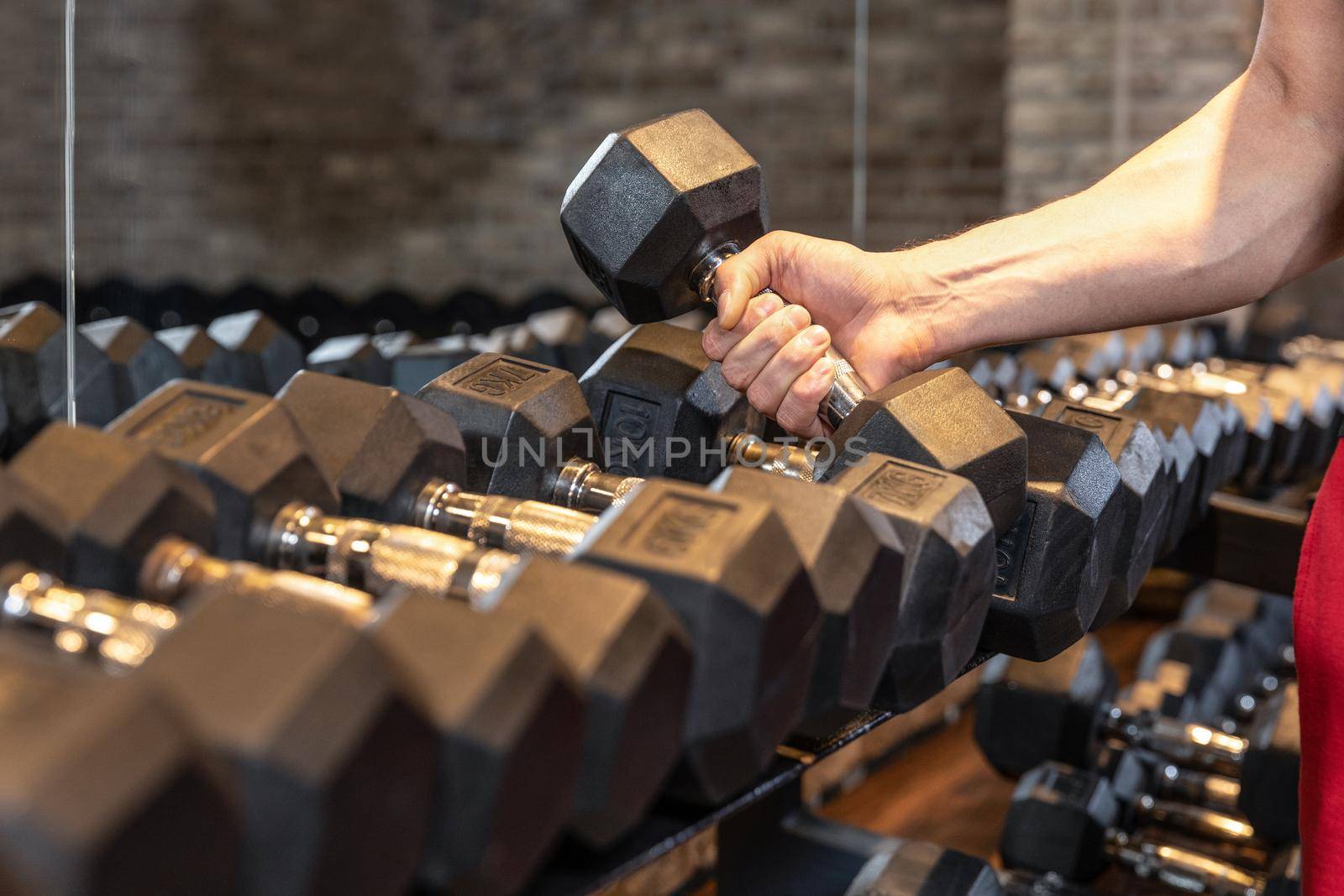Unrecognizable man taking dumbbell in a gym close up by ferhad