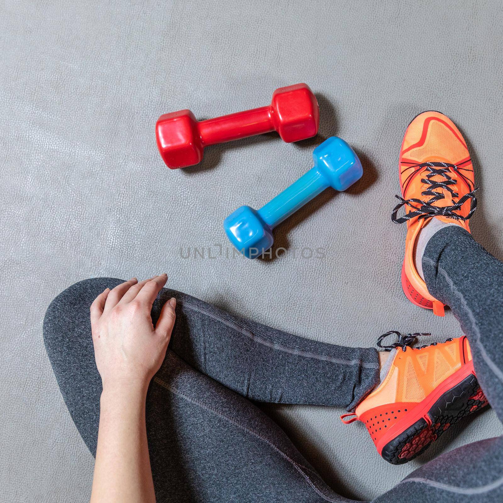 Fitness woman legs with colorful dumbbells top view