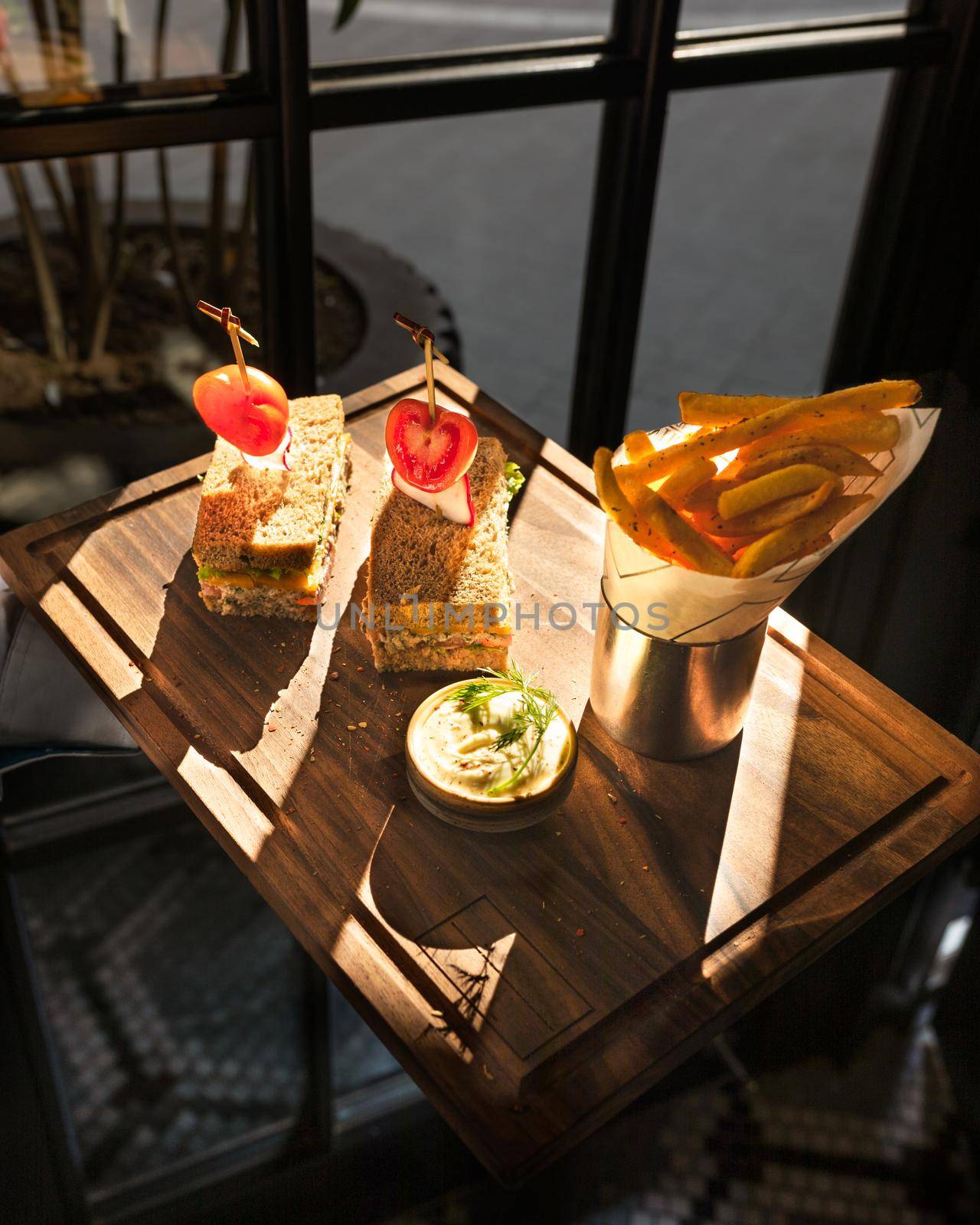 French fries with sandwich, sun shine on wooden plate