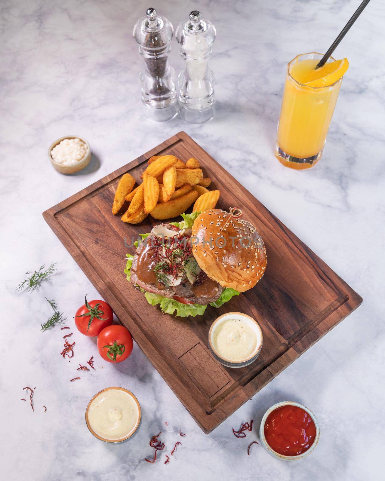 Tasty burger with fried potato, juice on wooden plate by ferhad