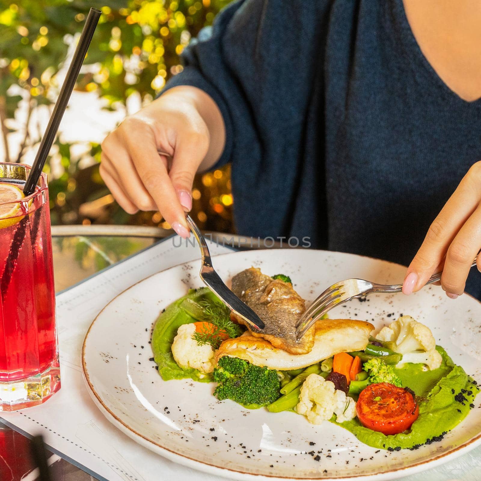 Woman eating fish meal with red cocktail by ferhad