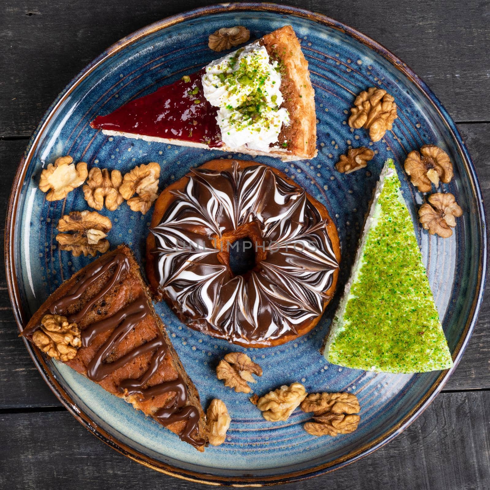 Beautiful doughnut, chocolate cake, tiramisu on the blue plate, top view