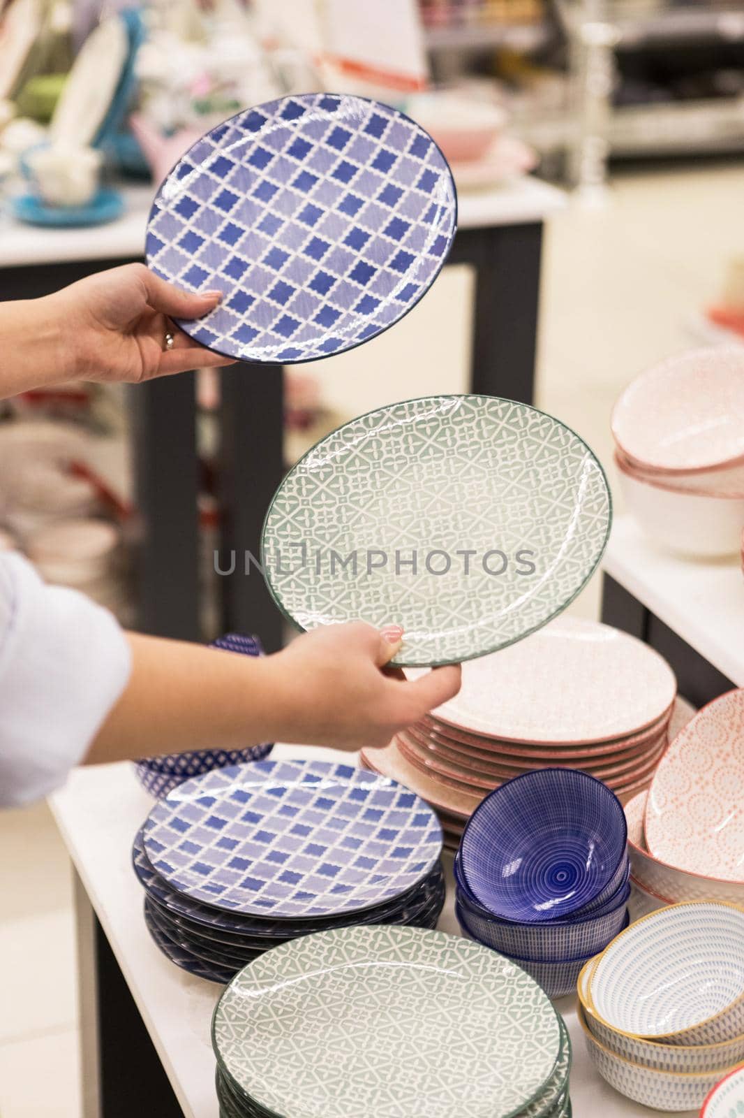 Woman holding colorful kitchen plates at the store by ferhad