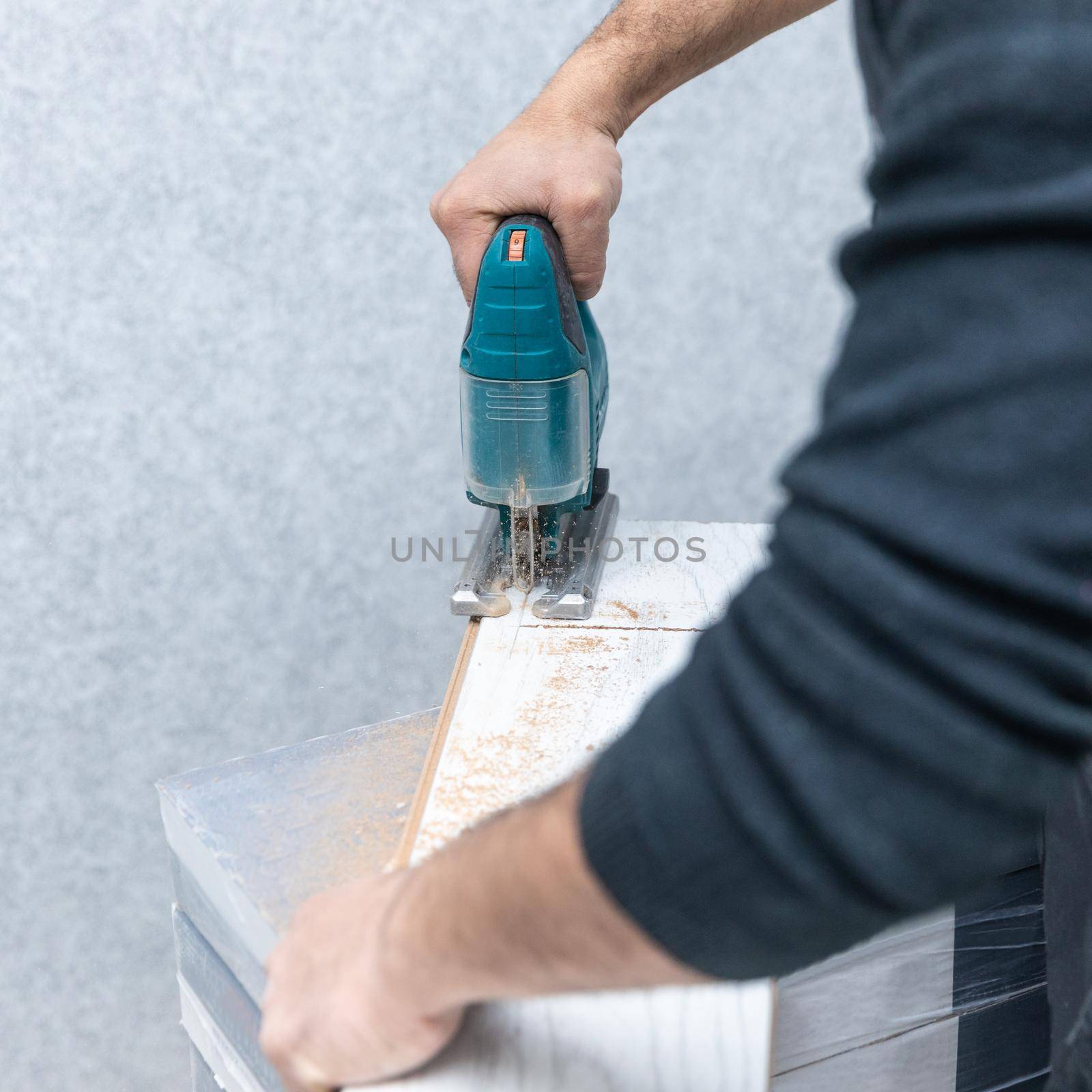 Man working with jigsaw on white wood laminate