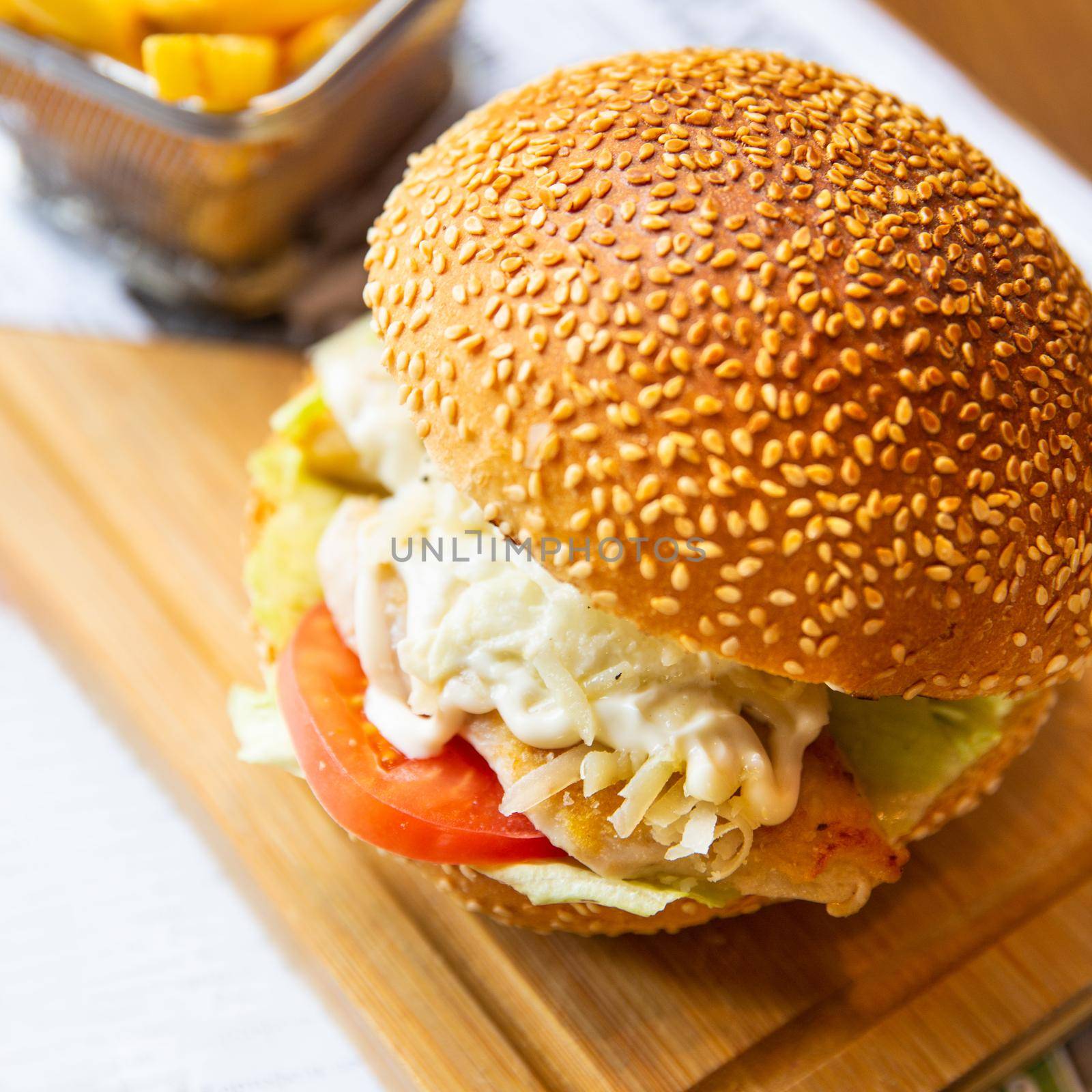 Caesar burger with french fries on the wood plate close up by ferhad