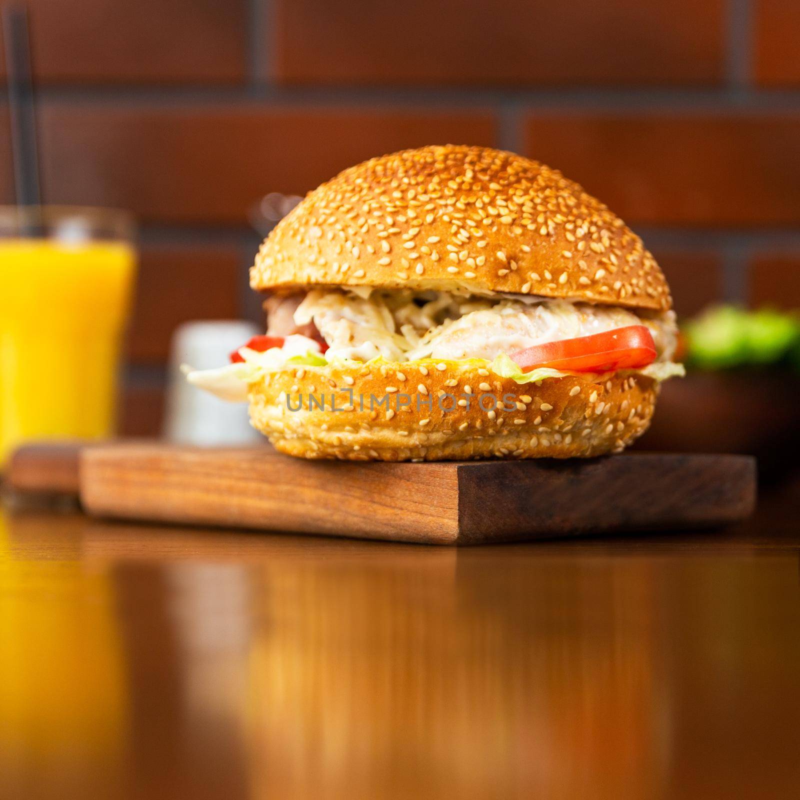 Caesar burger, french fries on the wood plate with orange juice