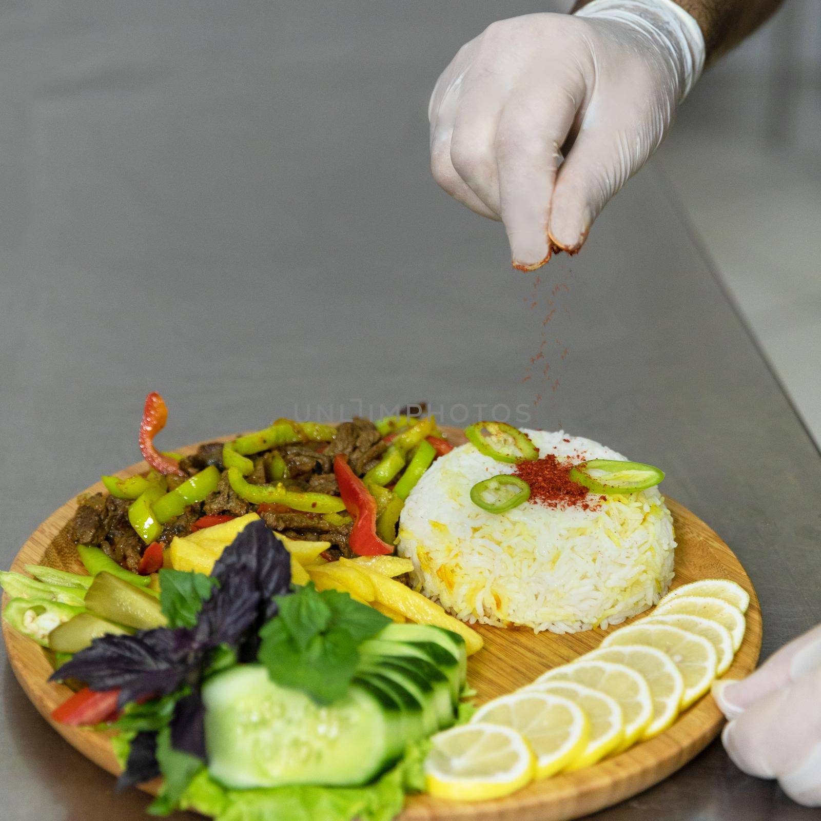 Restaurant chef pouring pepper to a salad meat meal