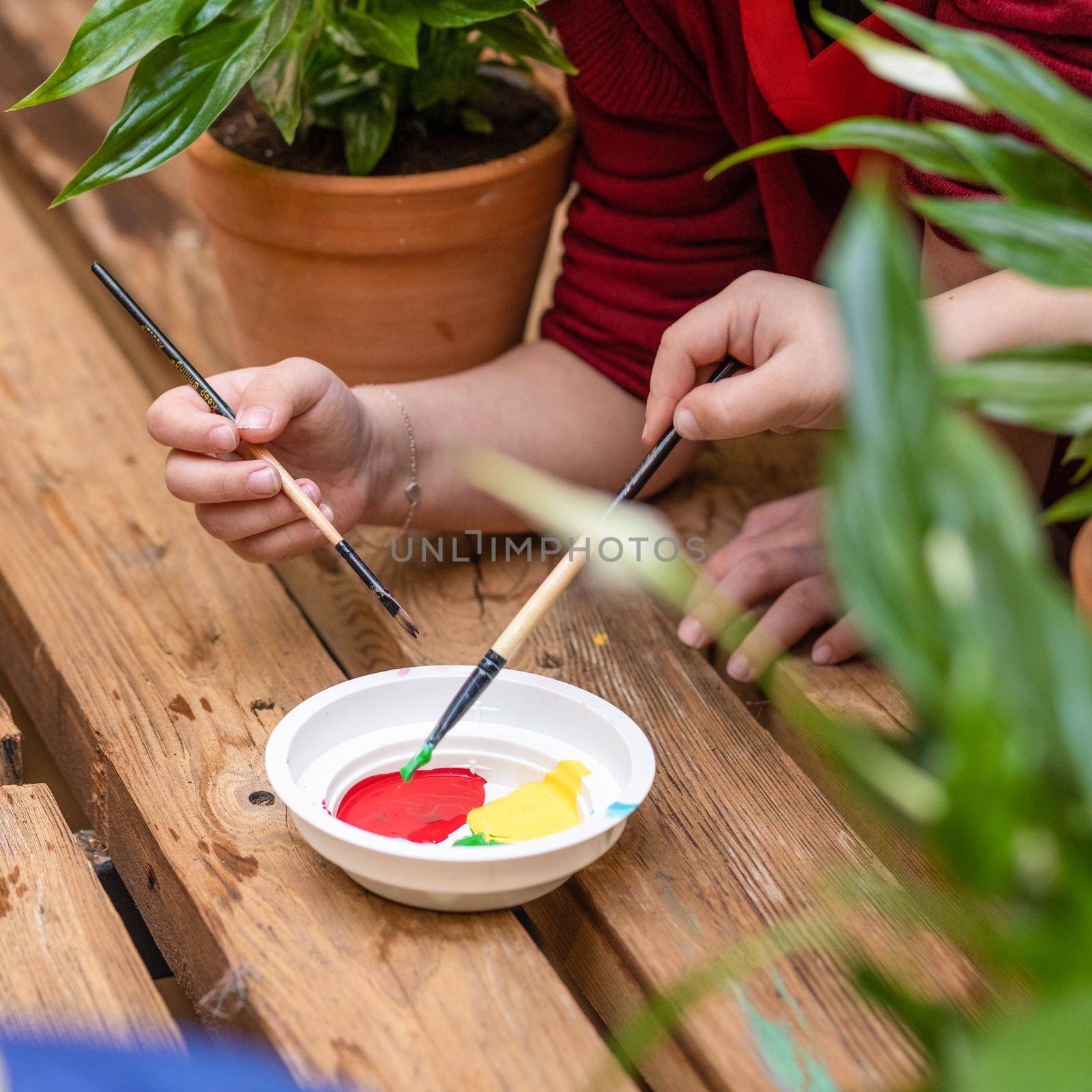 Kids dipping paint plate with a brush top view