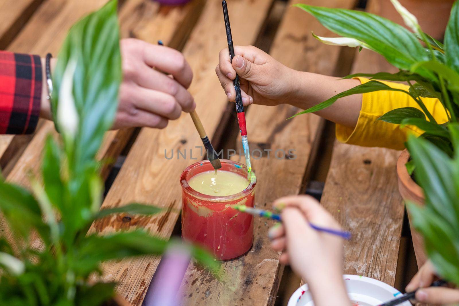 Kids hand holding a brush and dips it in a glass of water