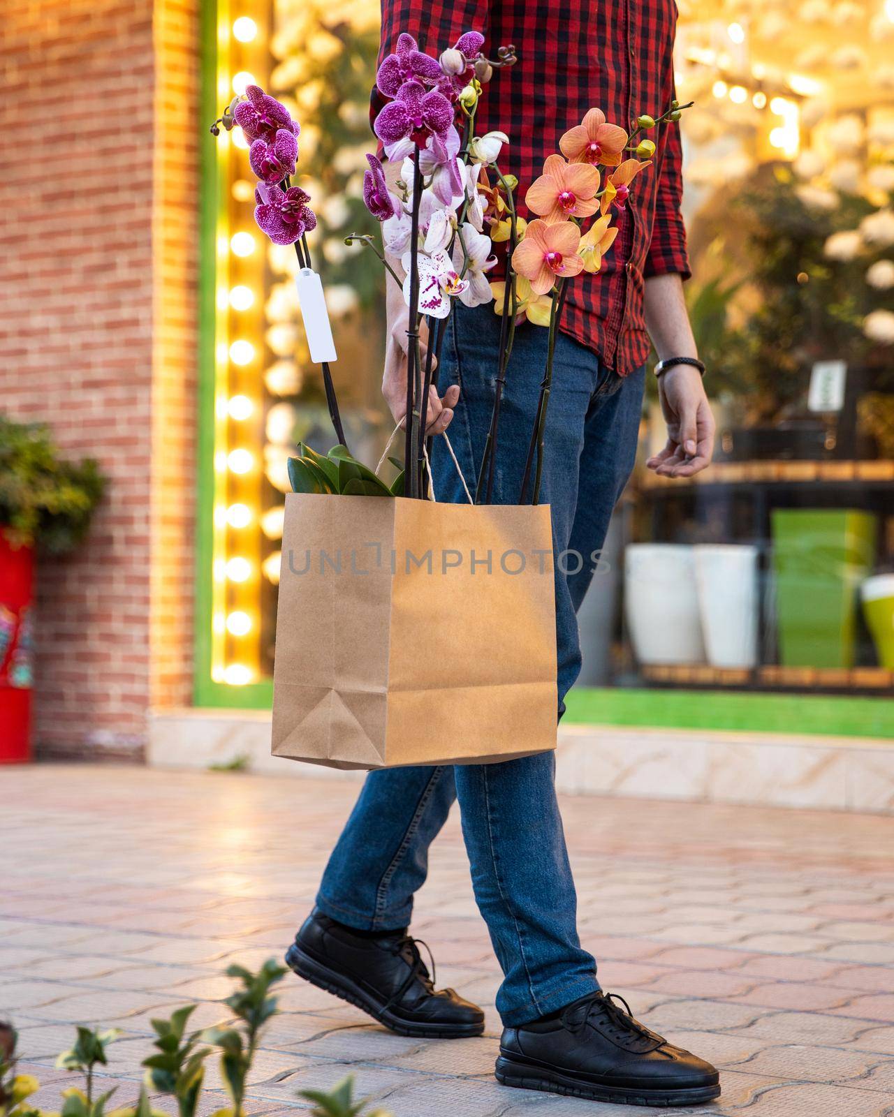 Man walking with shopping bag inside Moth orchids Phalaenopsis by ferhad