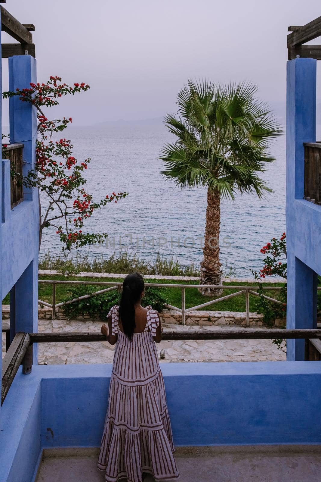 woman on balcony on holiday luxury vacation looking out over the ocean of Crete Greece by fokkebok