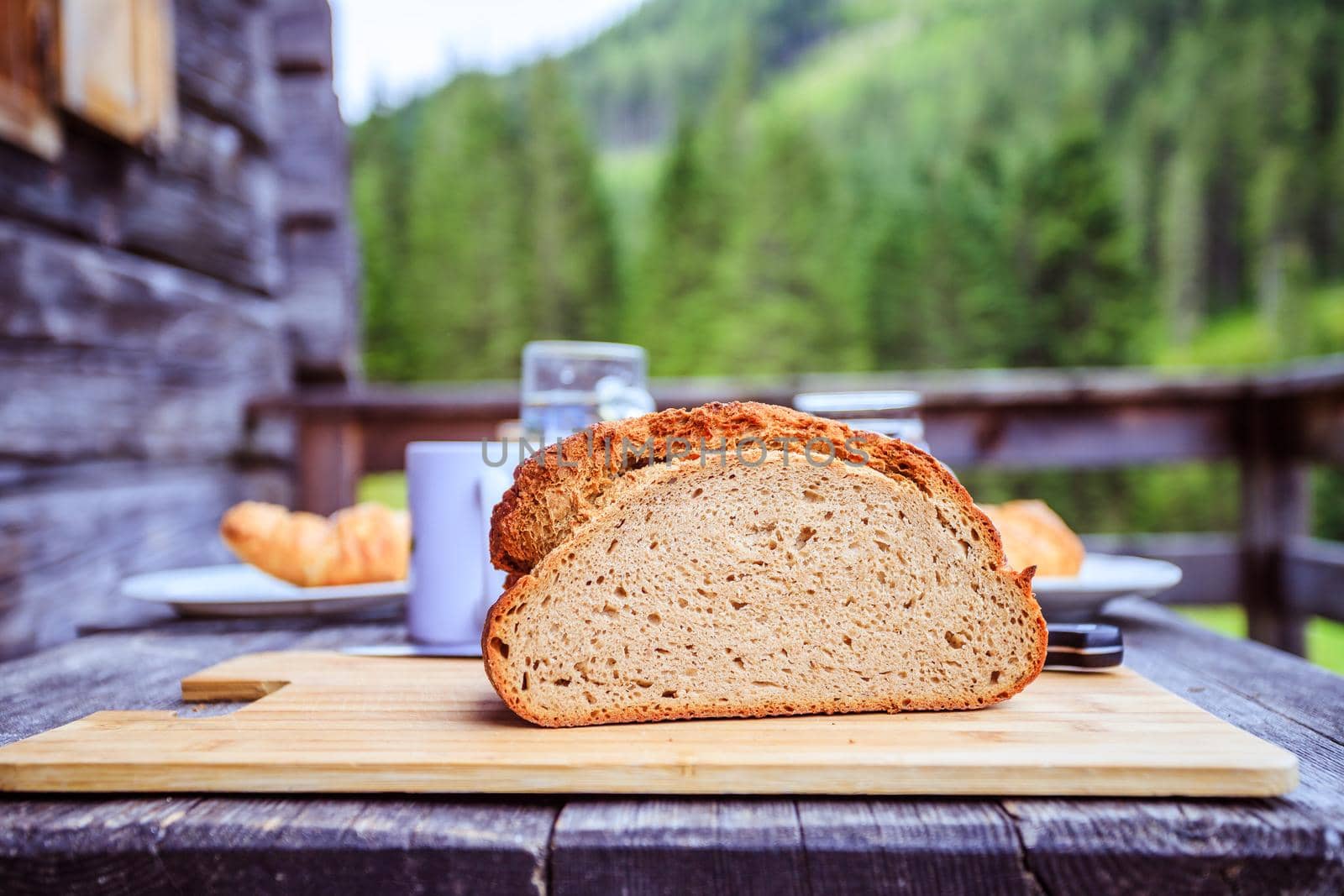 Fresh dark crisp bread for breakfast on an alpine hut. Wooden cutting board and milk in glass bottle.