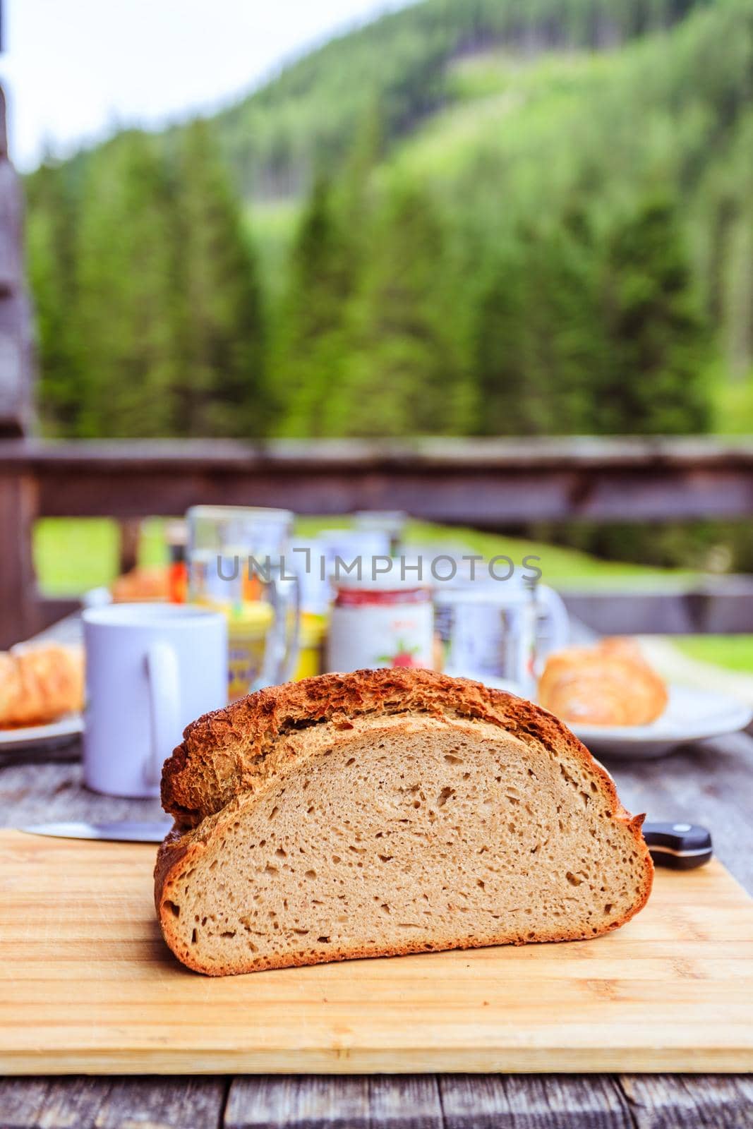 Fresh dark crisp bread for breakfast on an alpine hut. Wooden cutting board and milk in glass bottle.