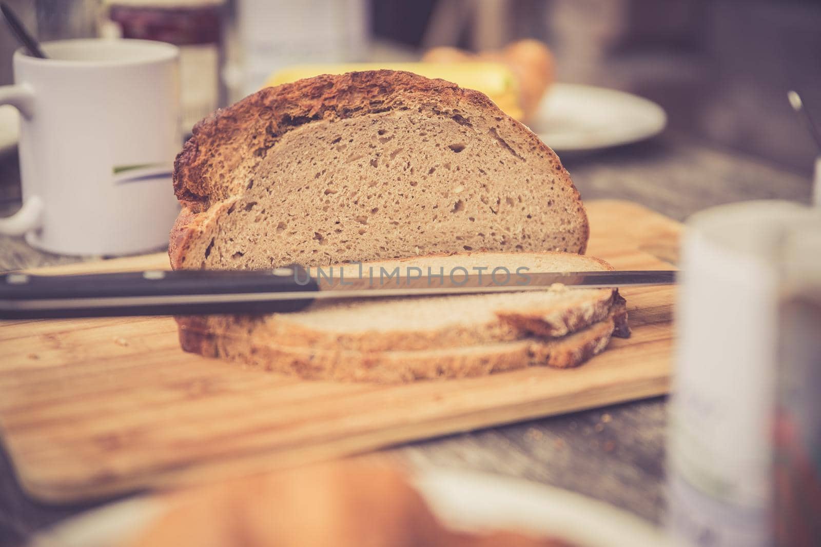 Fresh dark crisp bread for breakfast on an alpine hut. Wooden cutting board and milk in glass bottle.