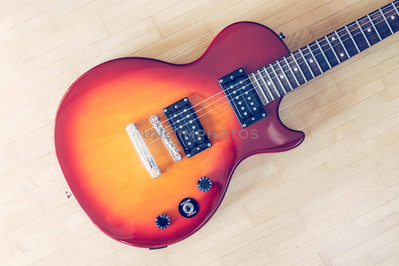 Electronic guitar in sunburst optic lying on the wooden floor