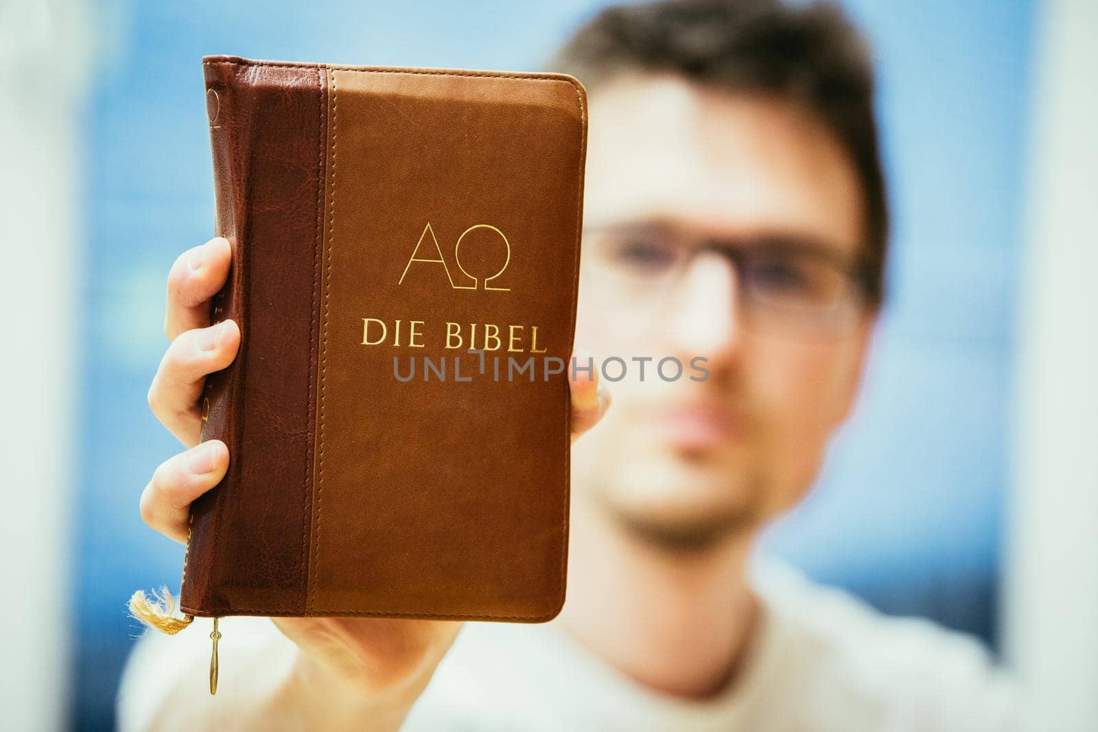 Christian preacher: Young man is holding the bible, praying by Daxenbichler