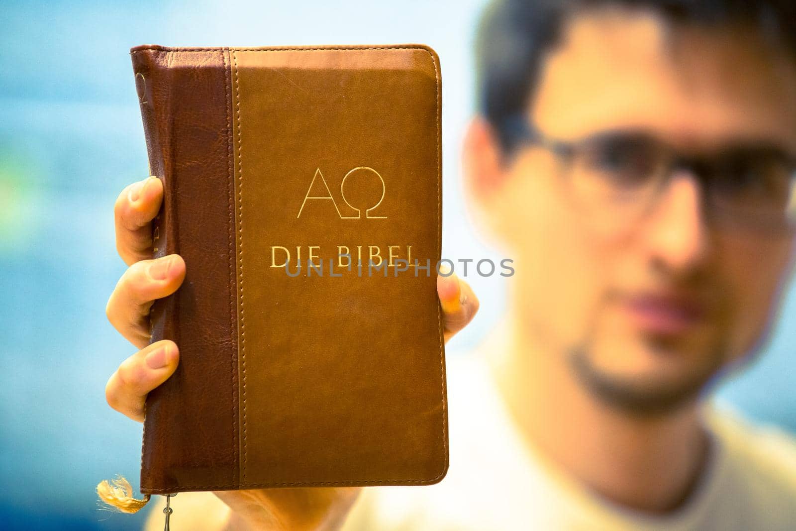 Christian preacher: Young man is holding the bible, praying by Daxenbichler