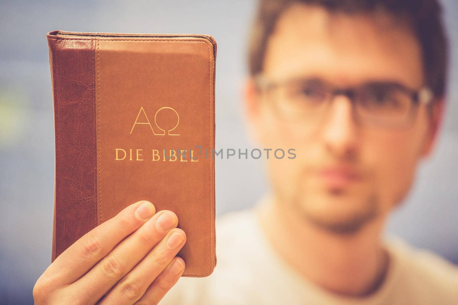 Christian preacher: Young man is holding the bible, praying by Daxenbichler