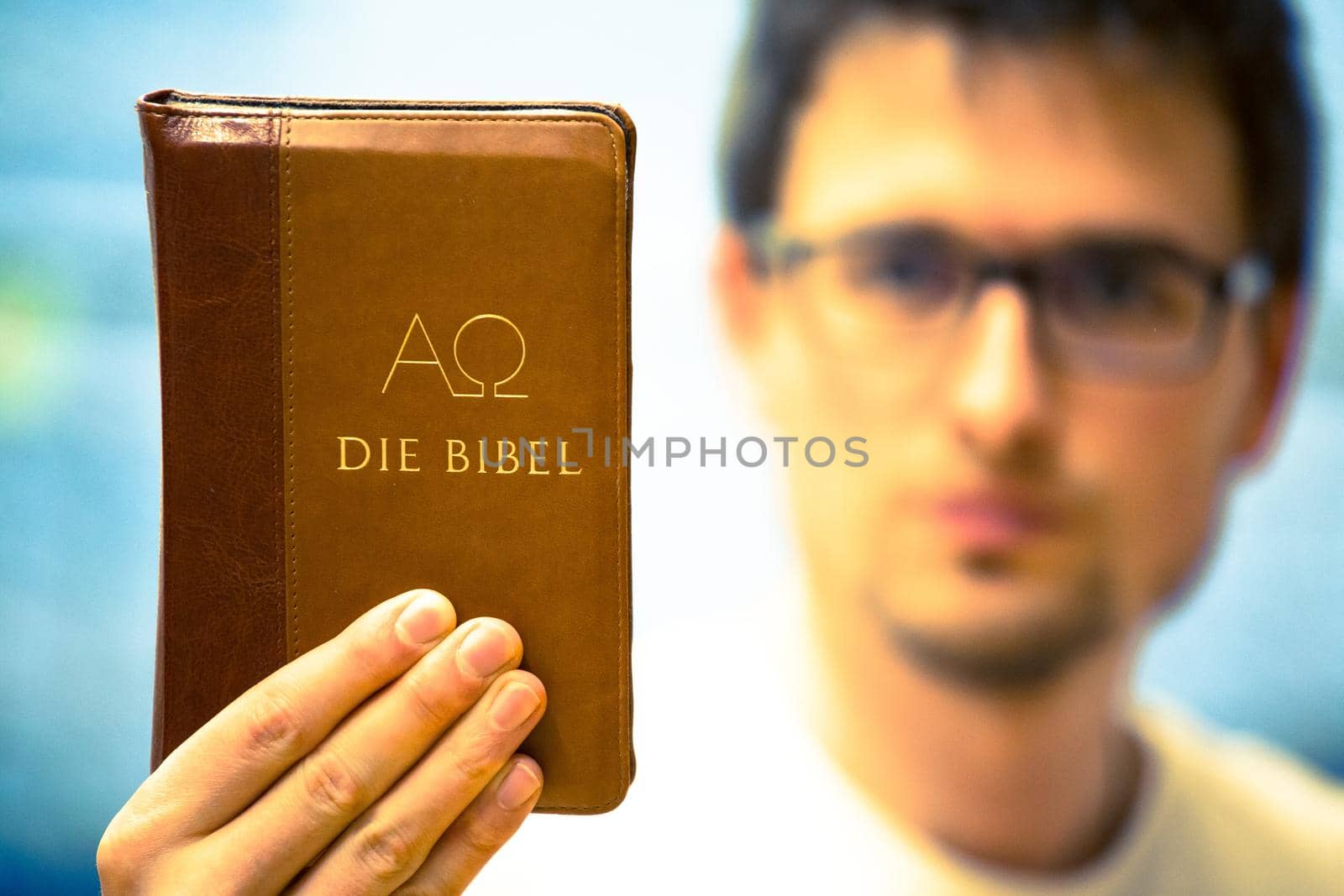 Christian preacher: Young man is holding the bible, praying by Daxenbichler