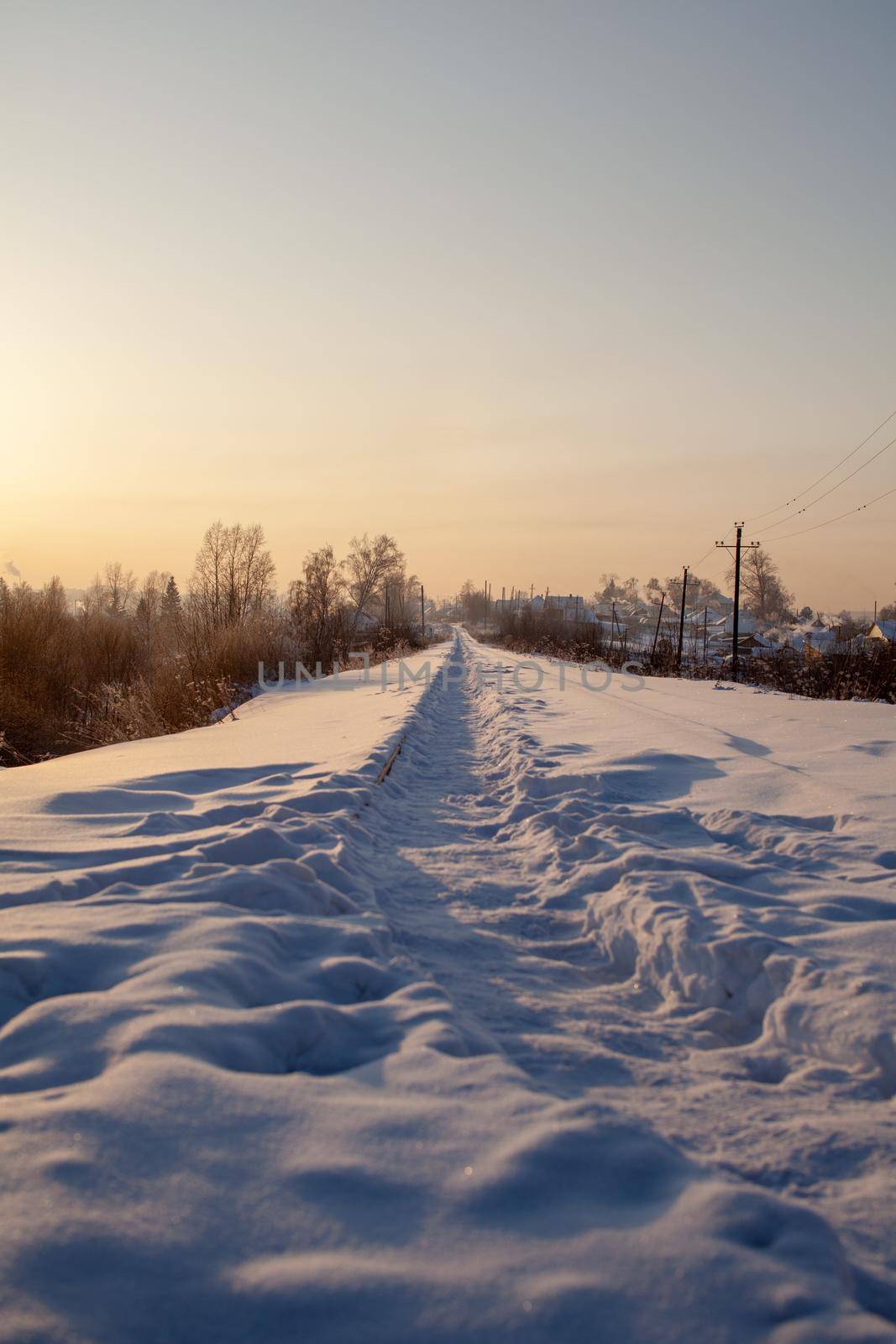 A snow-covered railway and a path trodden by people on it in winter. Lots of snow. Iron rails a track for a train in the direction of cargo covered with snow at a railway crossing in winter