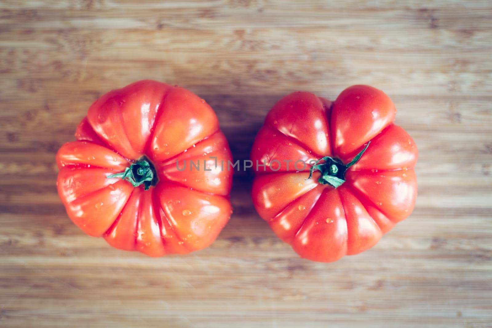 Close up picture of oxheart tomatoes on a bamboo wood plate.