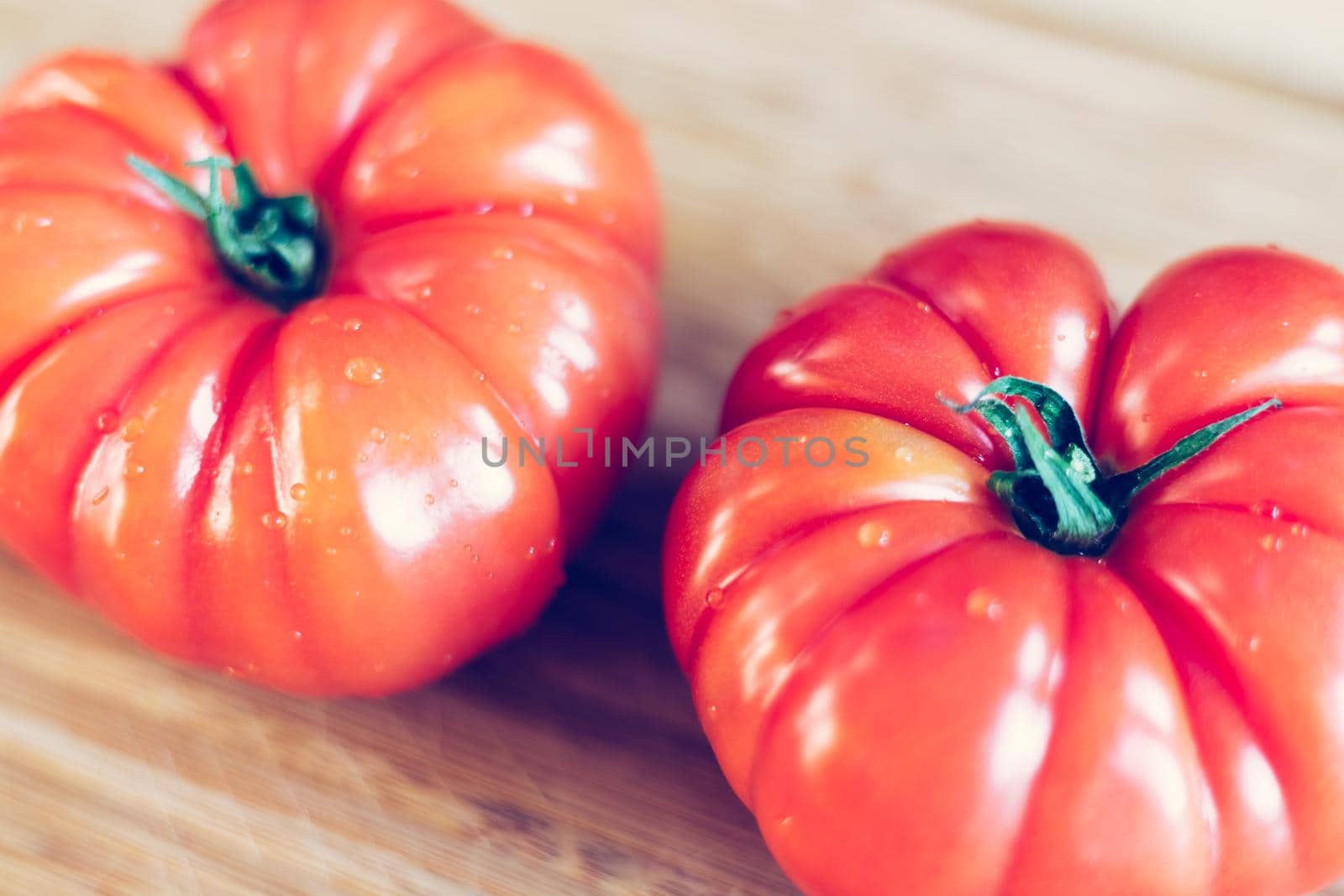 Close up picture of oxheart tomatoes on a bamboo wood plate.
