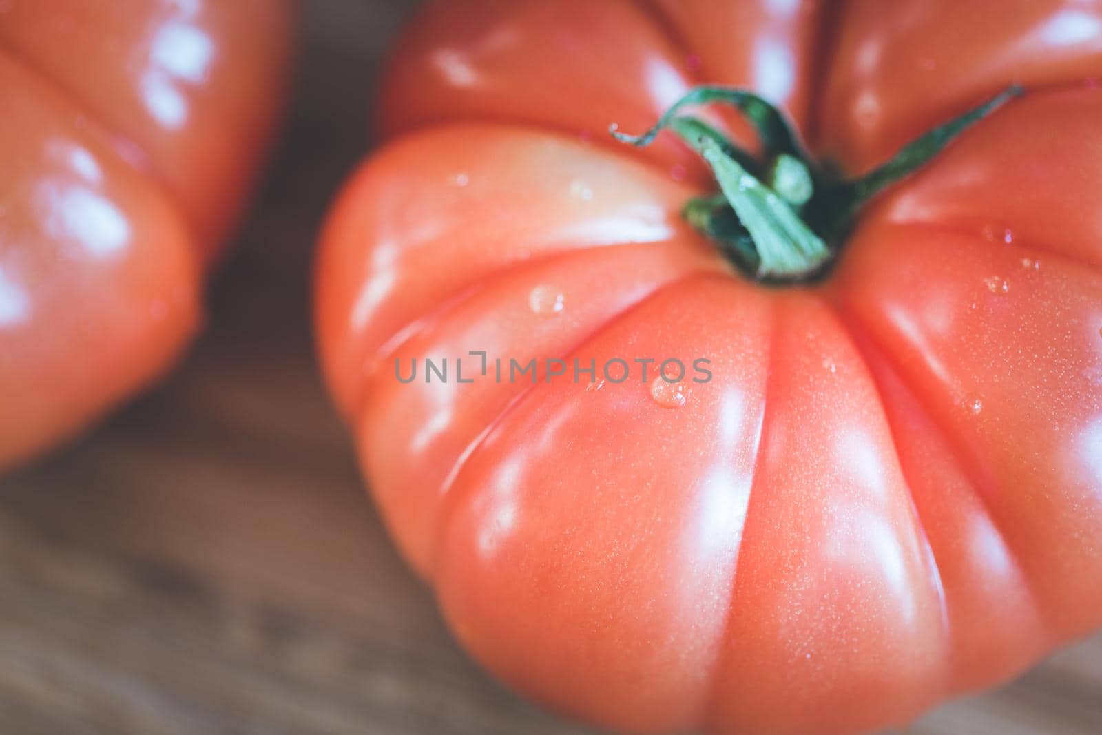 Close up picture of oxheart tomatoes on a bamboo wood plate.