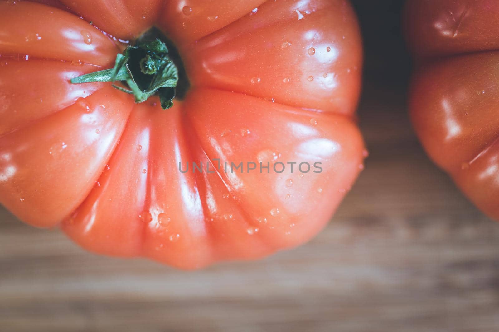 Close up picture of oxheart tomatoes on a bamboo wood plate.