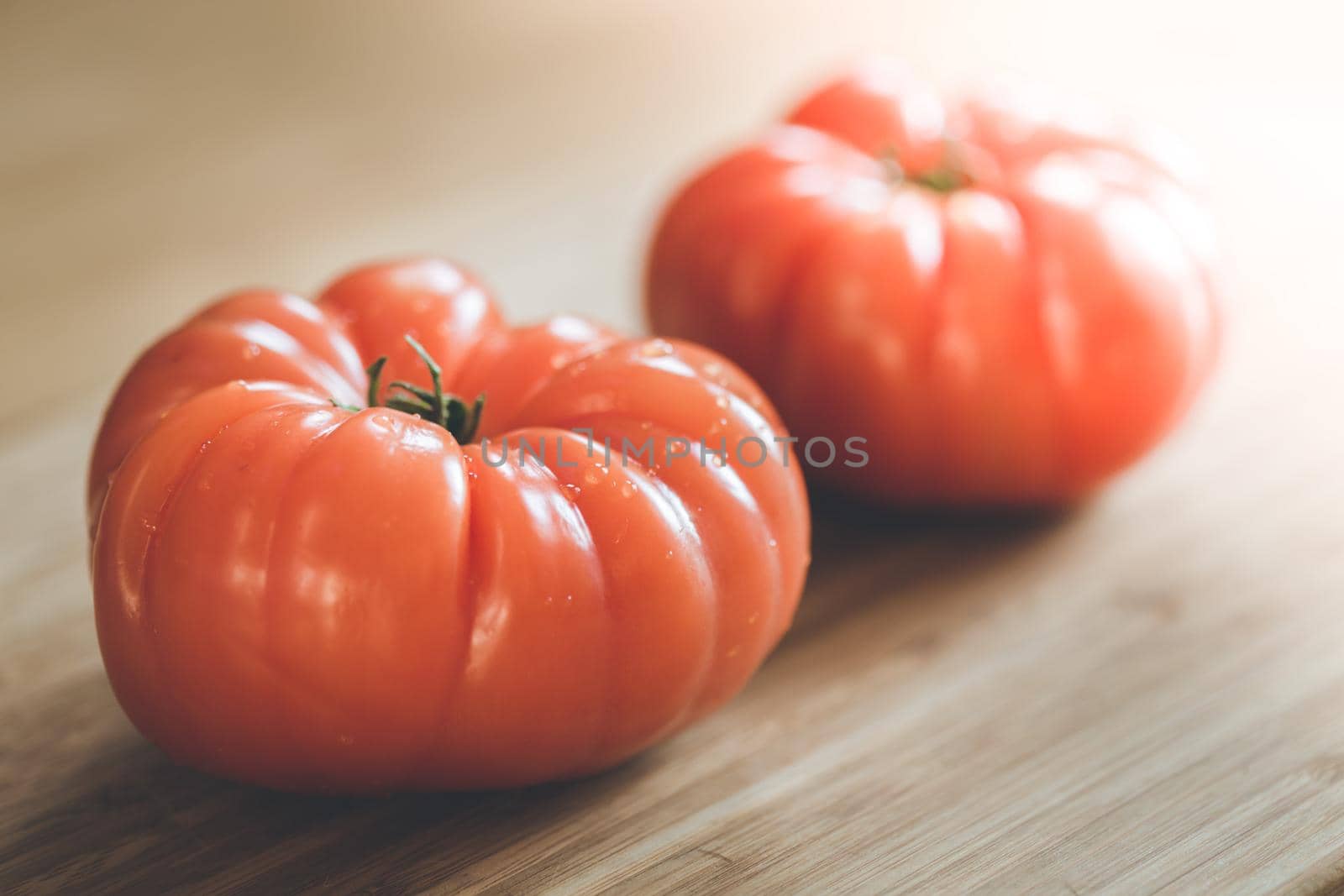 Close up picture of oxheart tomatoes on a bamboo wood plate.