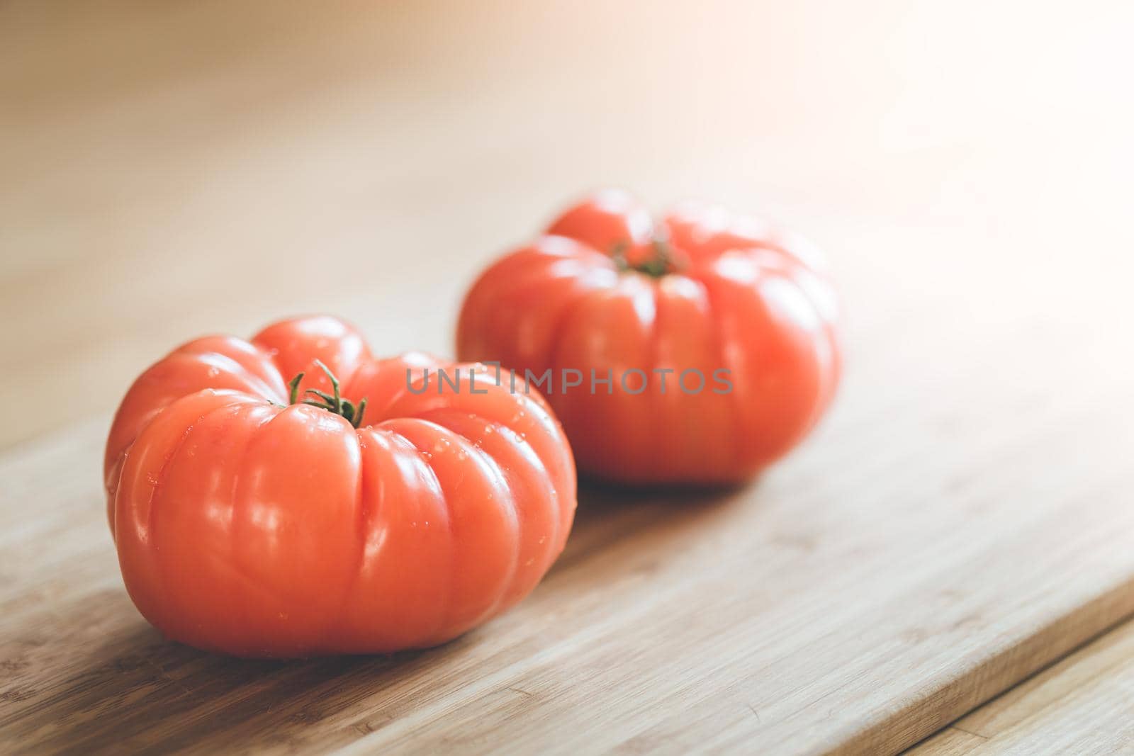 Close up picture of oxheart tomatoes on a bamboo wood plate.
