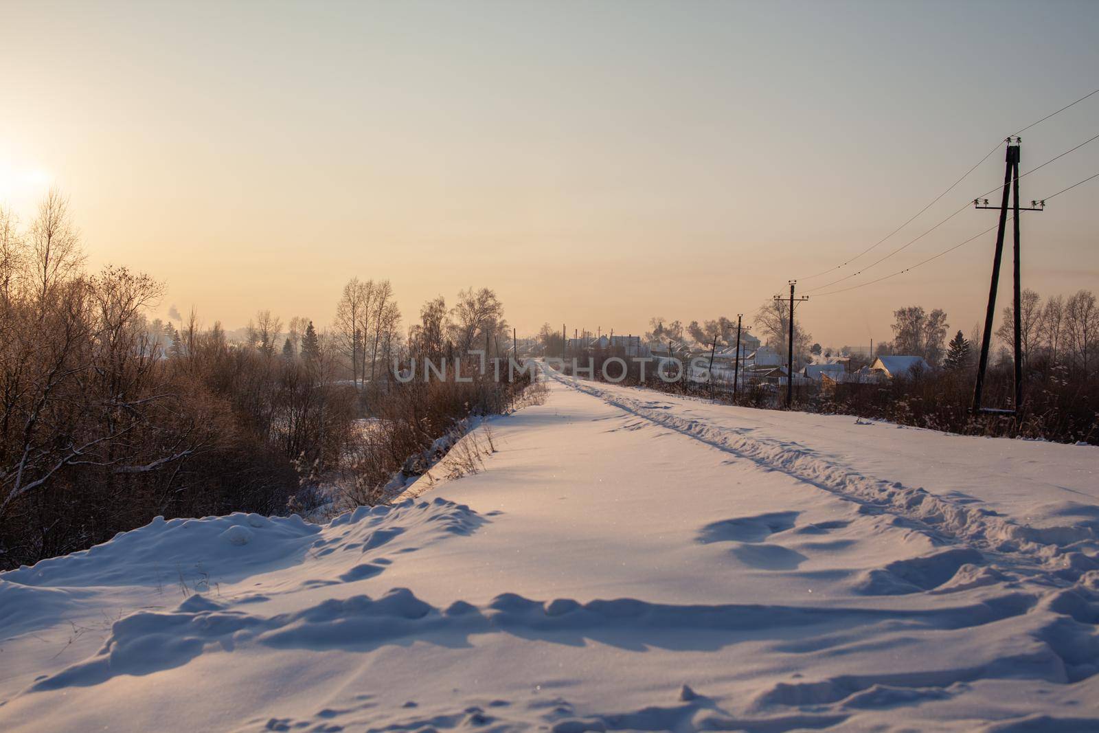 A snow-covered railway and a path trodden by people on it in winter. Lots of snow. Iron rails a track for a train in the direction of cargo covered with snow at a railway crossing in winter