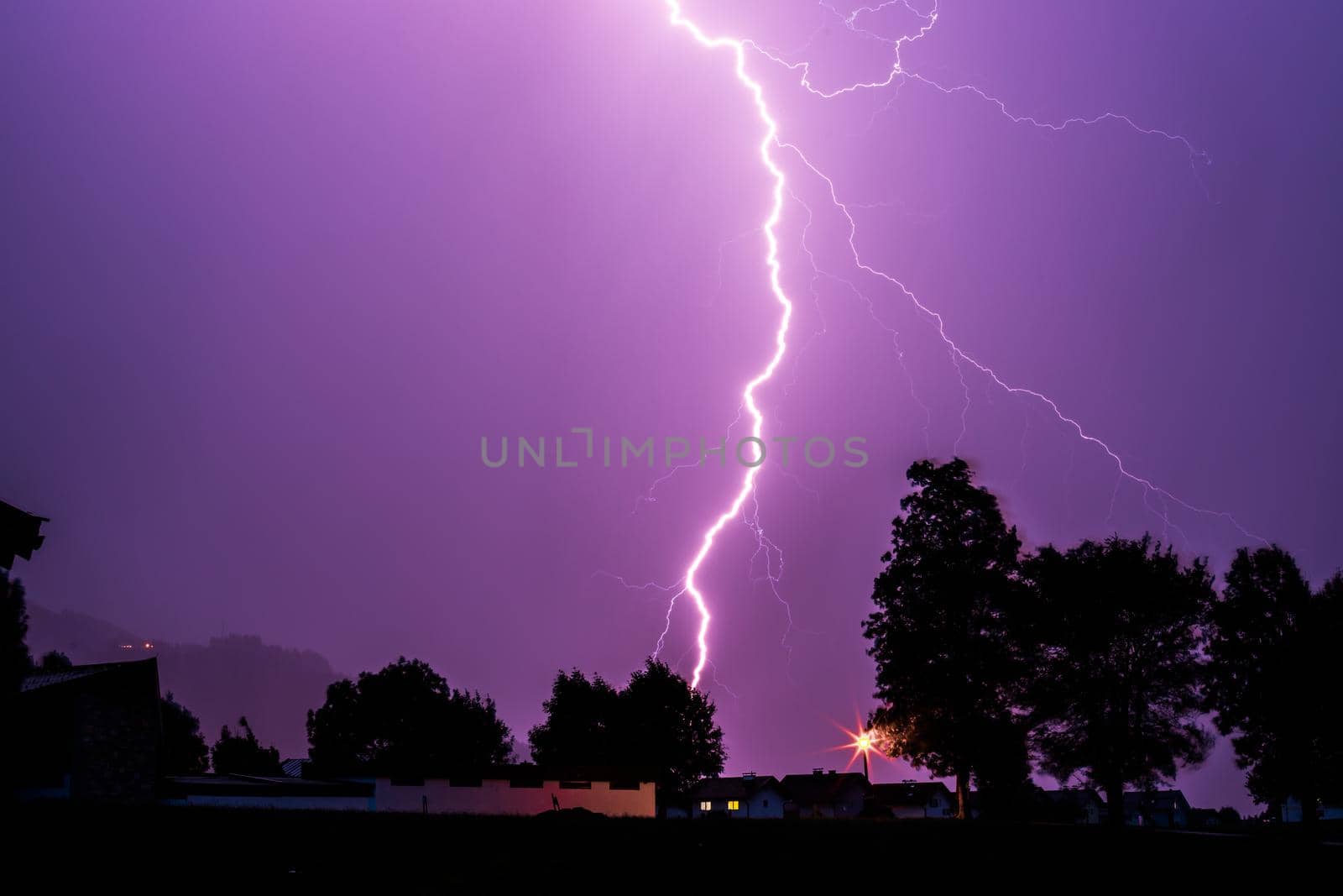 Thunderstorm in the night: Lightning on the colored sky. Global warming. by Daxenbichler