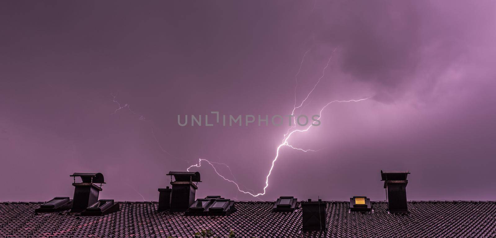 Thunderstorm in the night: Lightning over a roof of a building by Daxenbichler