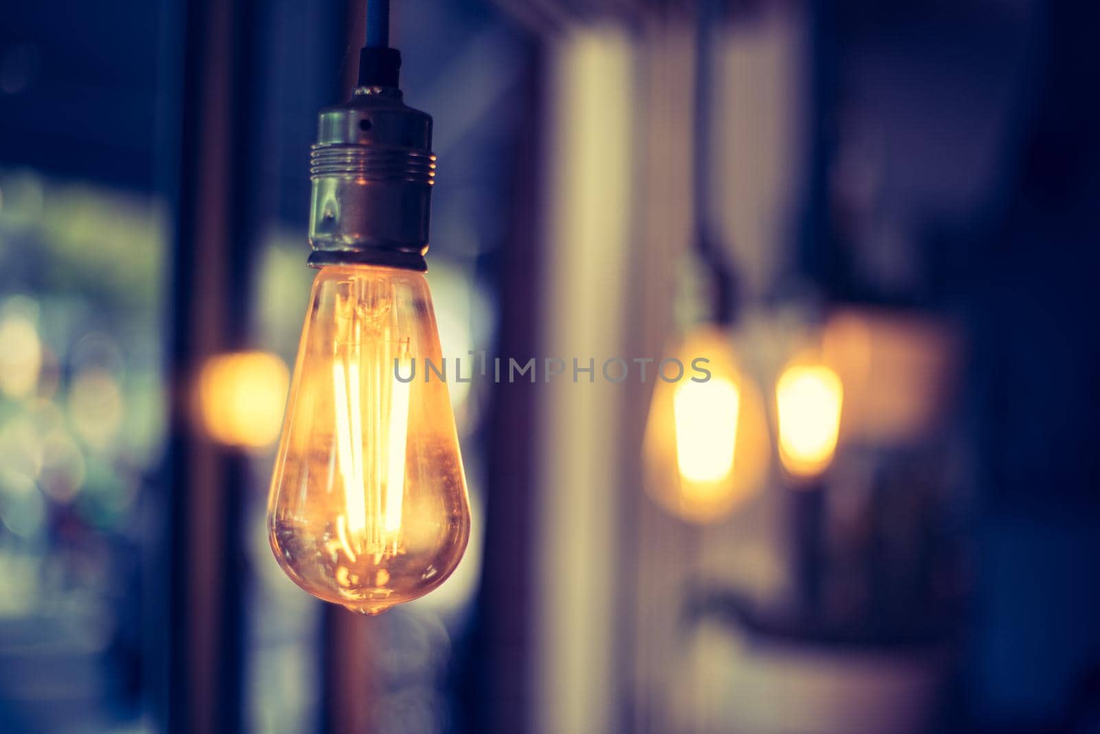 Close up picture of a hanging orange lightbulb in a restaurant or café