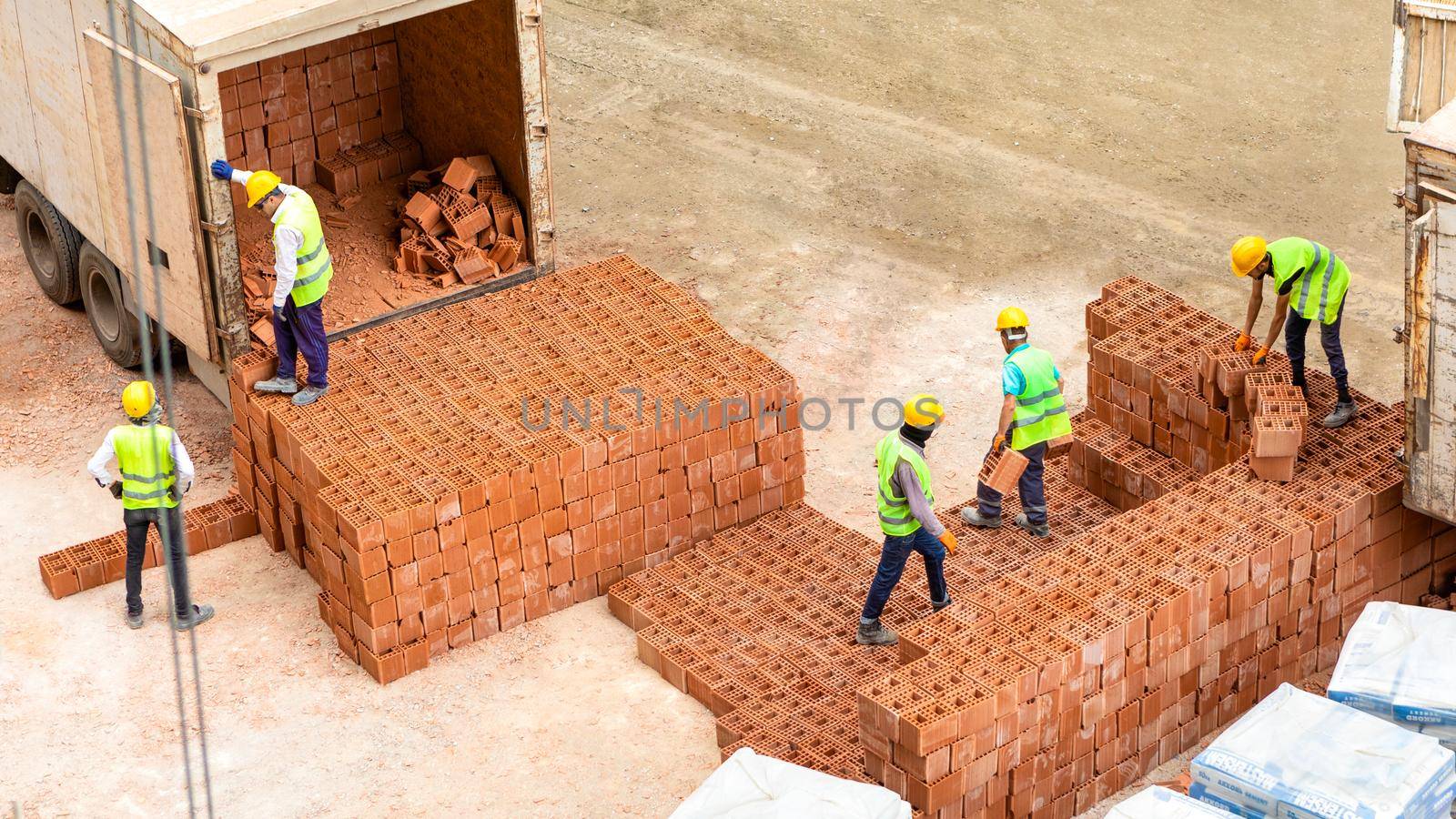 Construction workers unloading bricks, working on construction site by ferhad