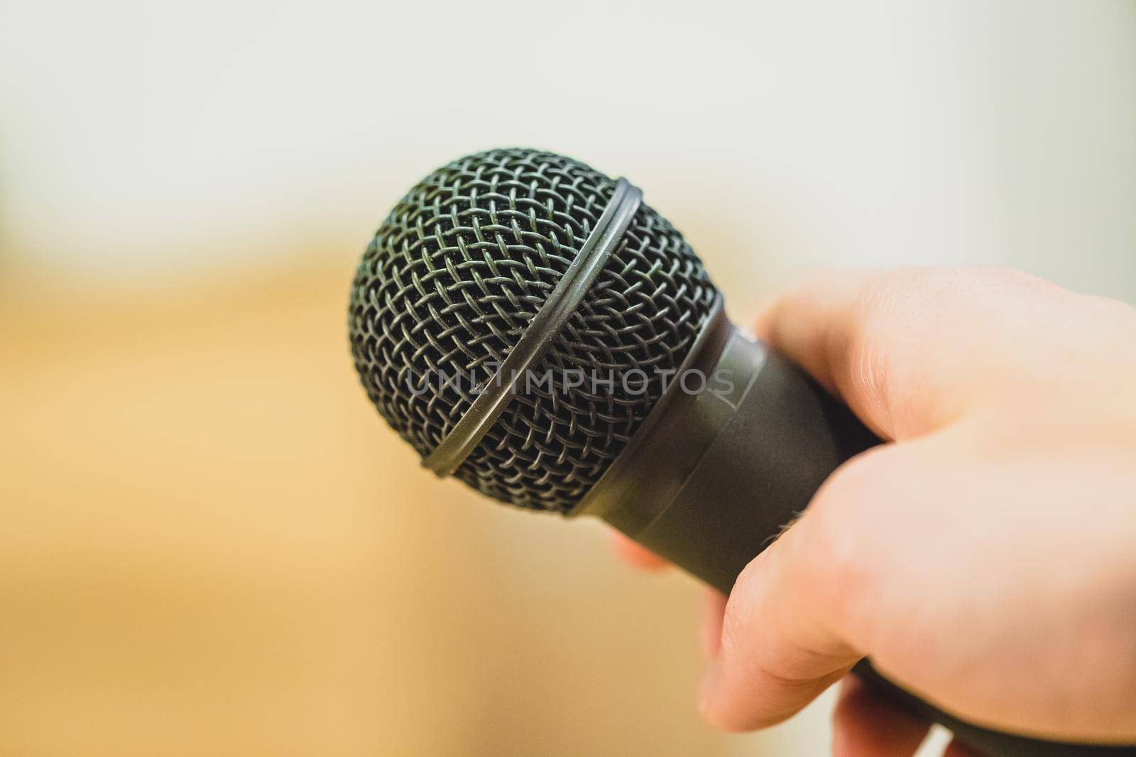 Close up picture of a hand which is holding a black microphone.