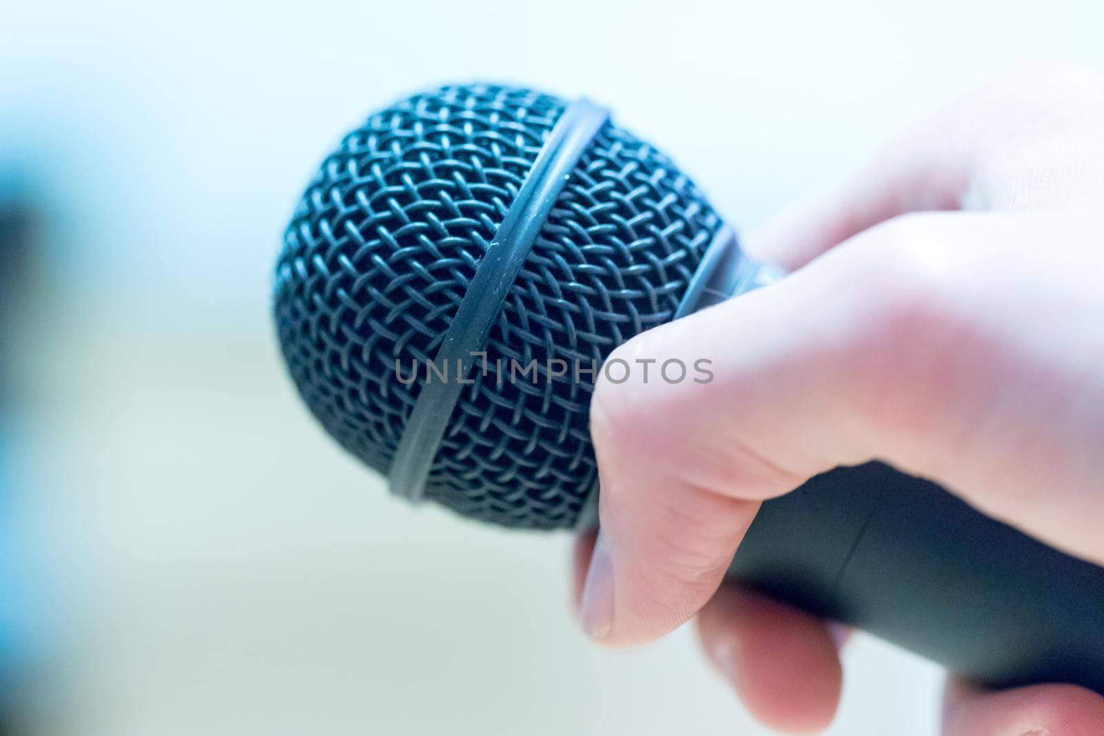 Close up picture of a hand which is holding a black microphone.